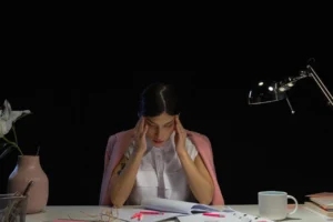 dieta anti mal di testa, donna alla scrivania con emicrania