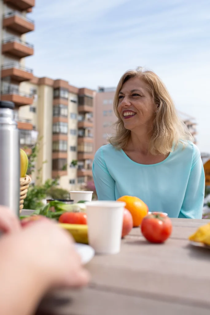 donna al tavolo con cibi ricchi di vitamina, in terrazza